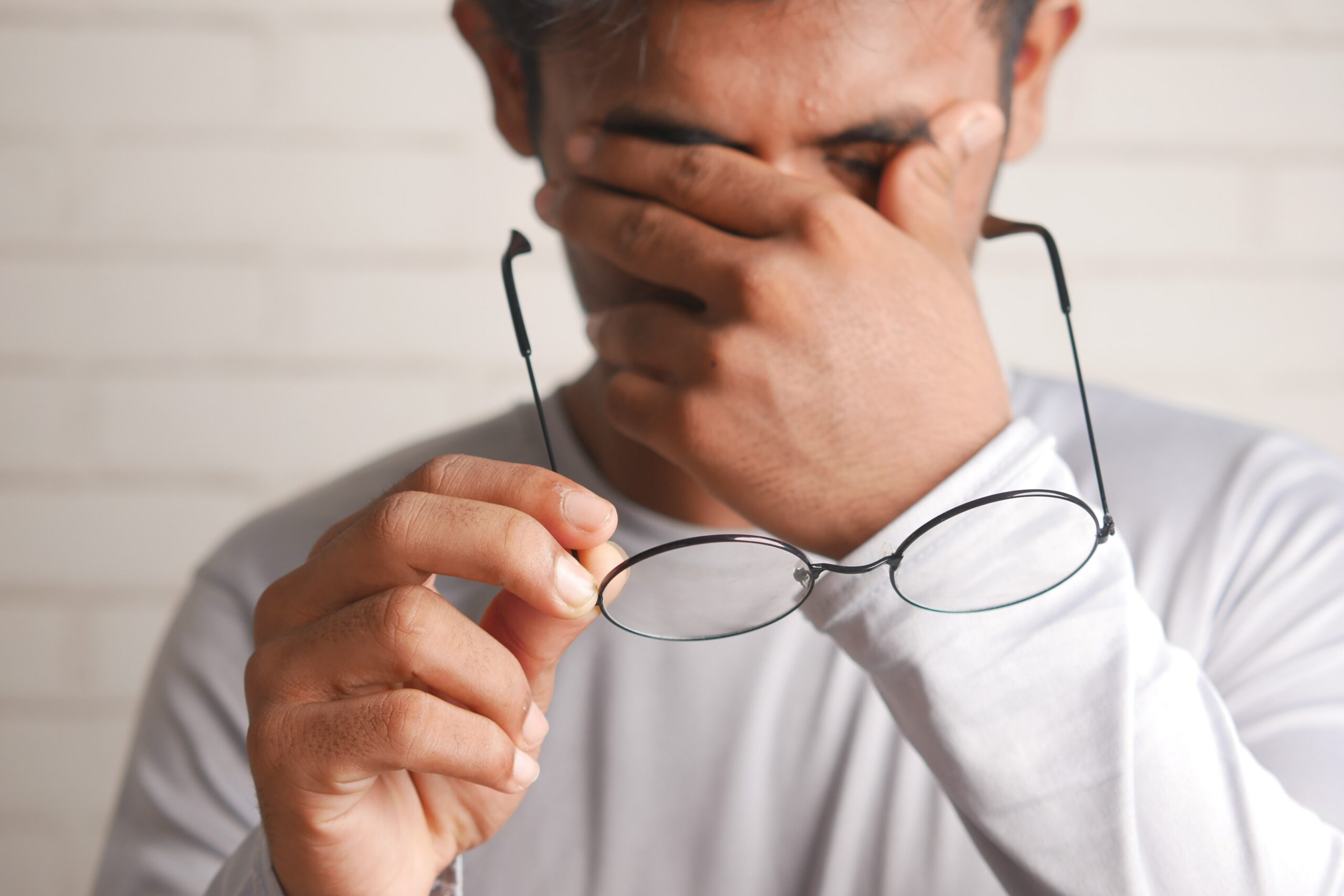 Man holding glasses looking emotional.