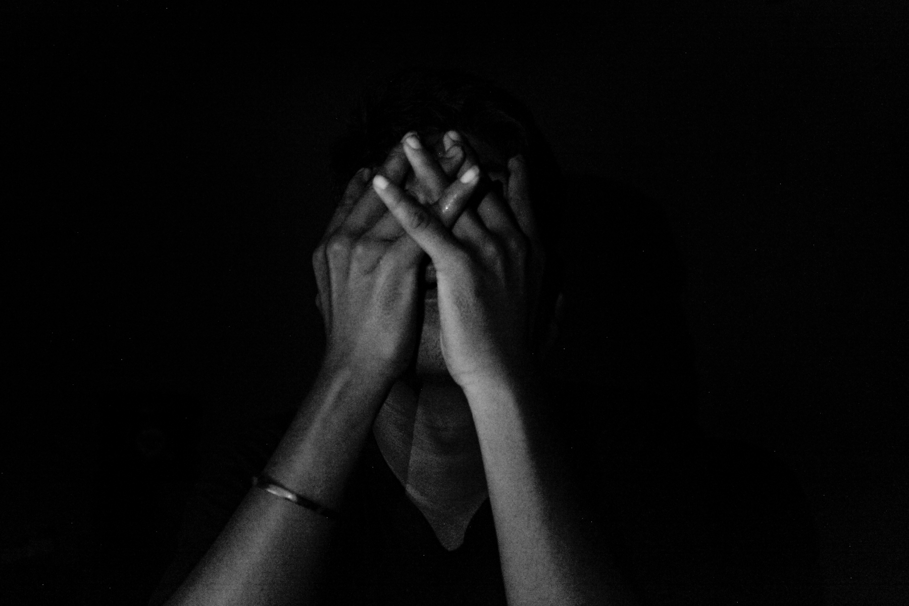 Depressed person covering their face with their hands. 